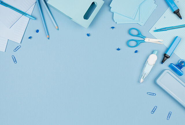 Pens, scissors and paper clips on a blue desk