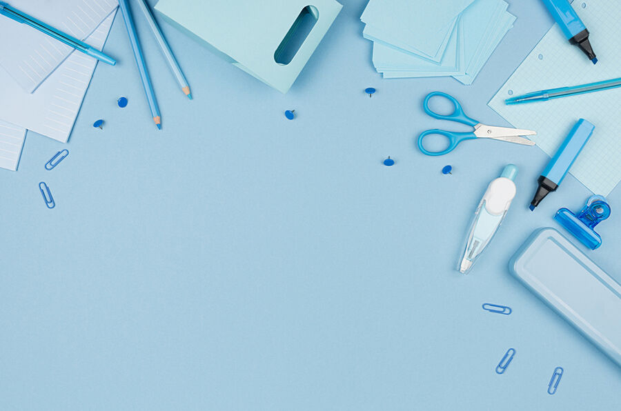 Stylos, ciseaux et trombones sur un bureau bleu